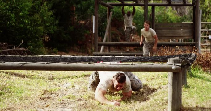Military people crawling under the hurdles during obstacle course