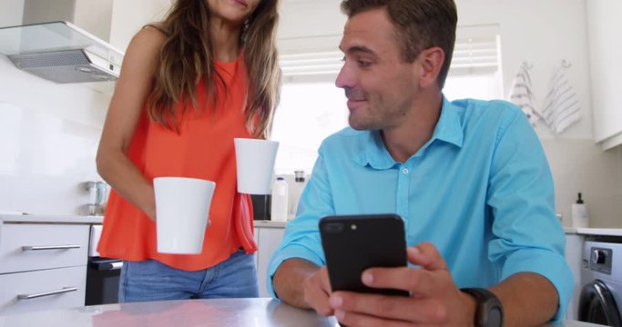 Young woman serving coffee to man on dining table in kitchen at home