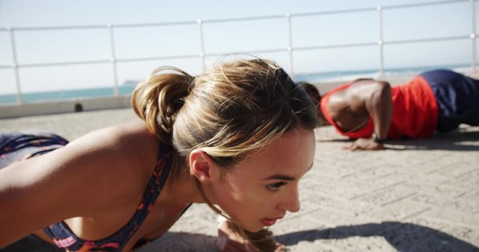 Couple doing push-up exercise on a promenade at beach