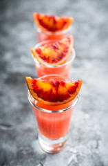 Strong red cocktail in shots on the rustic background. Selective focus. Shallow depth of field.
