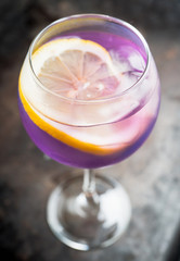 Colorful cocktail with lemon and lavender liqueur in wineglass on the rustic background. Selective focus. Shallow depth of field. 
