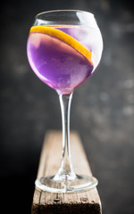 Colorful cocktail with lemon and lavender liqueur in wineglass on the rustic background. Selective focus. Shallow depth of field. 