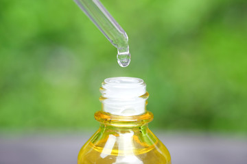 Dropping serum collagen moisturizer of face into clear yellow bottle soft light background. Protector skin Treatment facial essence oil, Vitamin C. Beauty and spa Concept