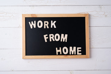 `Work from Home` words on a modern board on a white wooden surface, top view. Overhead, from above, flat lay.
