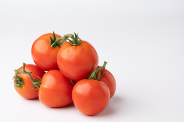 Fresh tomatoes on a green stem on white
