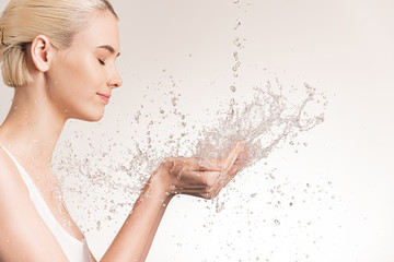 Photo of  young woman with clean skin and splash of water. Blonde woman with drops of water near her face. Spa treatment. Girl washing hands with water. Water and body. Water falling on human hands - Powered by Adobe