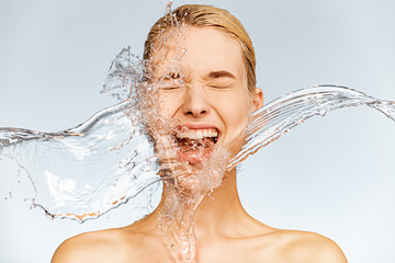 Photo of  screaming woman with drops of water around her face. Young woman with clean skin and...