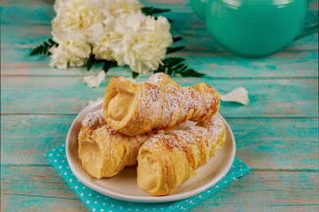 Puff pastry cones filled with caramel cream on wooden background.