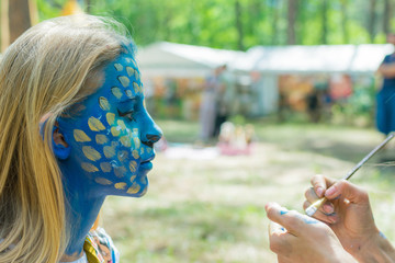 The girl is painted face aquagrim. Face coloring on the holiday.