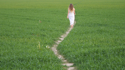 girl in a long white dress on a green field