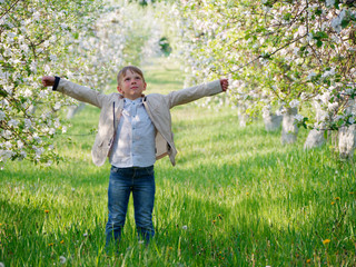 boy on the grass near blooming apple trees in the garden