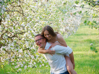 Obraz premium young guy and girl in blooming apple trees in the garden