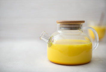 hot milk with turmeric and cinnamon in a glass bowl on a white background