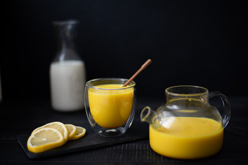 hot milk with turmeric and cinnamon in a glass bowl on a black background