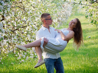 young guy and girl in blooming apple trees in the garden