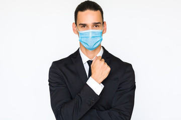 Classy portrait of masculine young businessman wearing a blue anti virus protective medical mask. Isolated on white background and looking at the camera. 