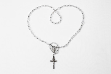 Catholic rosary with crucifix and medal of Virgin Mary on white background.