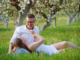 Naklejka na ściany i meble young guy and girl in blooming apple trees in the garden