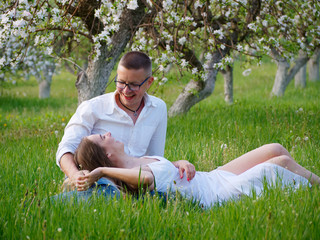 young guy and girl in blooming apple trees in the garden