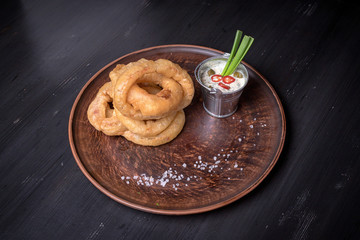 Fried rings of onions on a flat plate. restaurant giving. for the menu of cafe. wooden table wooden