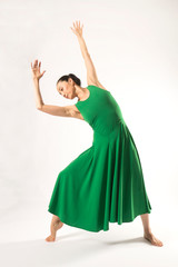 Adult woman dancing in the studio in a green dress.