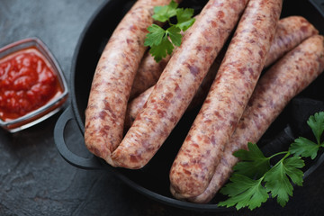 Raw sausages made of pork and poultry in a cast-iron pan, selective focus, studio shot, close-up