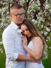 young guy and girl in blooming apple trees in the garden