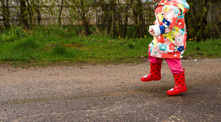 Obraz na płótnie Canvas the child jumps through puddles in bright boots. Summer content