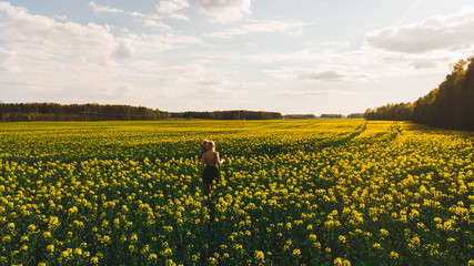 a man walks through a rapeseed field at sunset