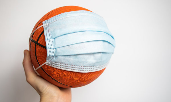 hand holding a basketball with medical mask sports after the covid pandemic concept - Powered by Adobe