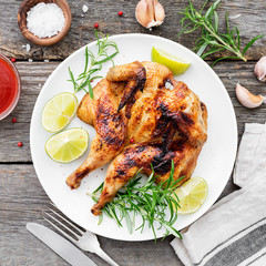 Butterflied grilled whole chicken served with limes and rosemary.