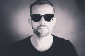 Fototapeta premium hübscher Mann mit Bart und Sonnenbrille, schwarz weiß Portrait