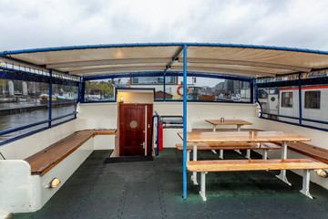 Tables with benches at the stern of a hotel ship in Amsterdam. A place to relax customers' passengers.