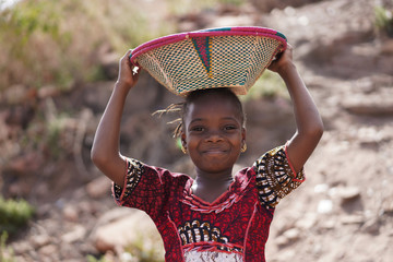 Gorgeous African Girl with Toothy Smile and Basket on Head - obrazy, fototapety, plakaty