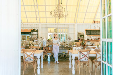 Portrait of stylish young woman in dress vintage style and hat stand posing in the coffee shop decoration in vintage style