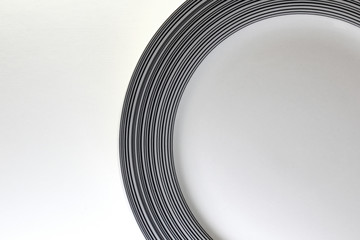 Round white porcelain plate with stripes on a white background. Copy space.