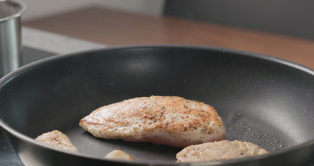 chicken fillet on non stick pan with wood spatula acloseup