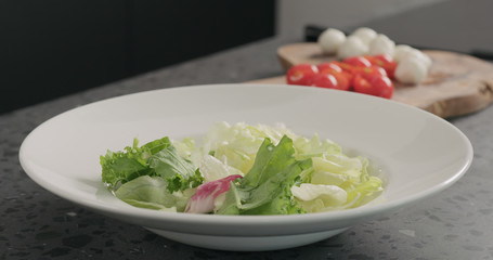 mixed grreens in white bowl on concrete countertop