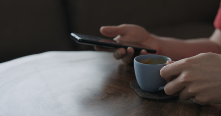 Closeup young man use smartphone while sitting at the table and drinking morning coffee