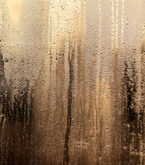 Drops of water on a glass window at dawn as an abstract background.