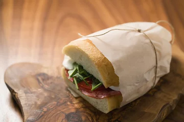 Keuken spatwand met foto ciabatta sandwich with salami and mozzarella cheese on walnut table © GCapture