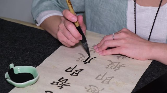 Young woman practicing Chinese traditional calligraphy at home amid corona virus pandemic