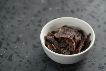 spiced beef jerky in white bowl on terrazzo countertop