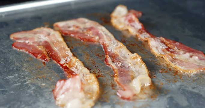 The fried pieces of bacon with hot steam.