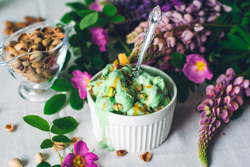 pistachio green ice cream in a white bowl with a spoon on the table