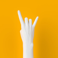Rock hand sign, female hand punk rock gesture white color isolated on yellow, creative art protest banner, 3d rendering