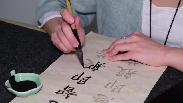 Young woman practicing Chinese traditional calligraphy at home amid corona virus pandemic