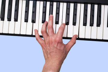 Close-up of the hand of a musical artist playing the piano, Grand piano, synthesizer, male hand, classical music, keyboard, synthesizer, pianist. Blue background.