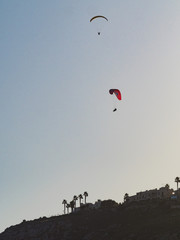 Paragliders flying in blue sky.