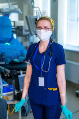 Portrait of young surgical nurse in scrubs standing in operating theatre. Portrait of female doctor in modern medical room.